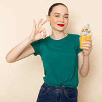 A woman in a green t-shirt holds a yellow bubble tea drink, making an "OK" hand gesture with a smile.